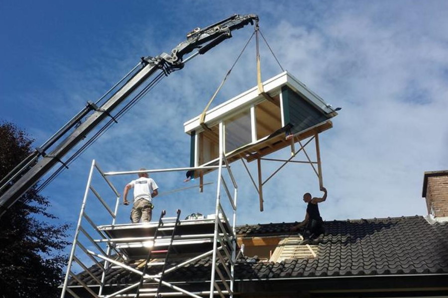 Prefab kunststof dakkapel die met een kraan op het dak wordt geplaatst.