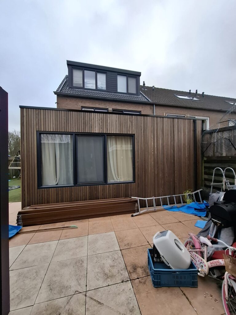 Detail van verticale houten gevelbekleding op een moderne aanbouw.